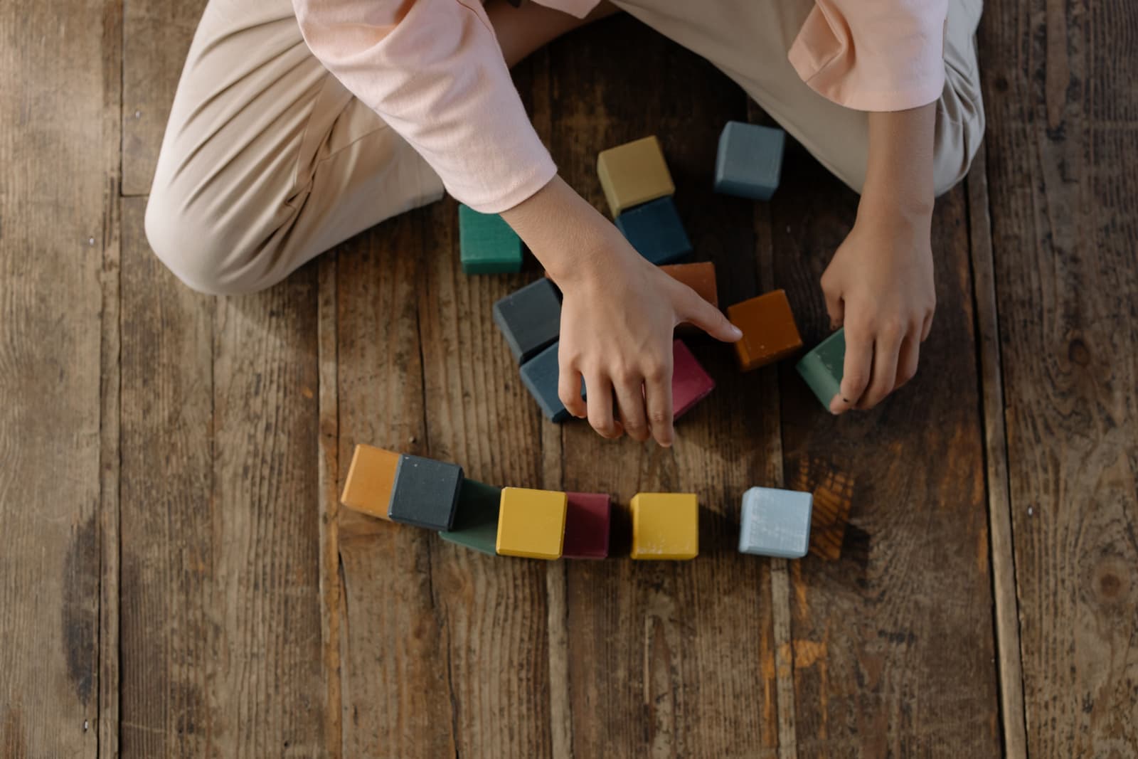 A young child's hands stacking colored wooden blocks