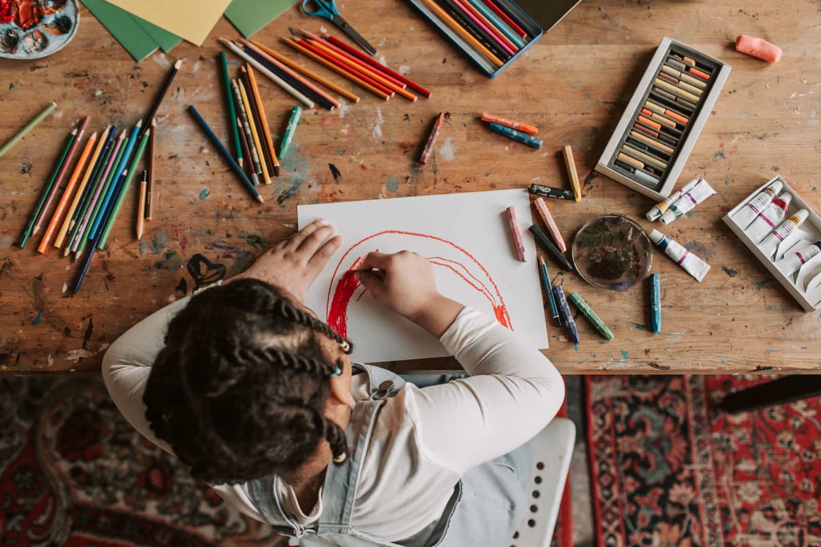 Two children drawing with crayons at a wooden table