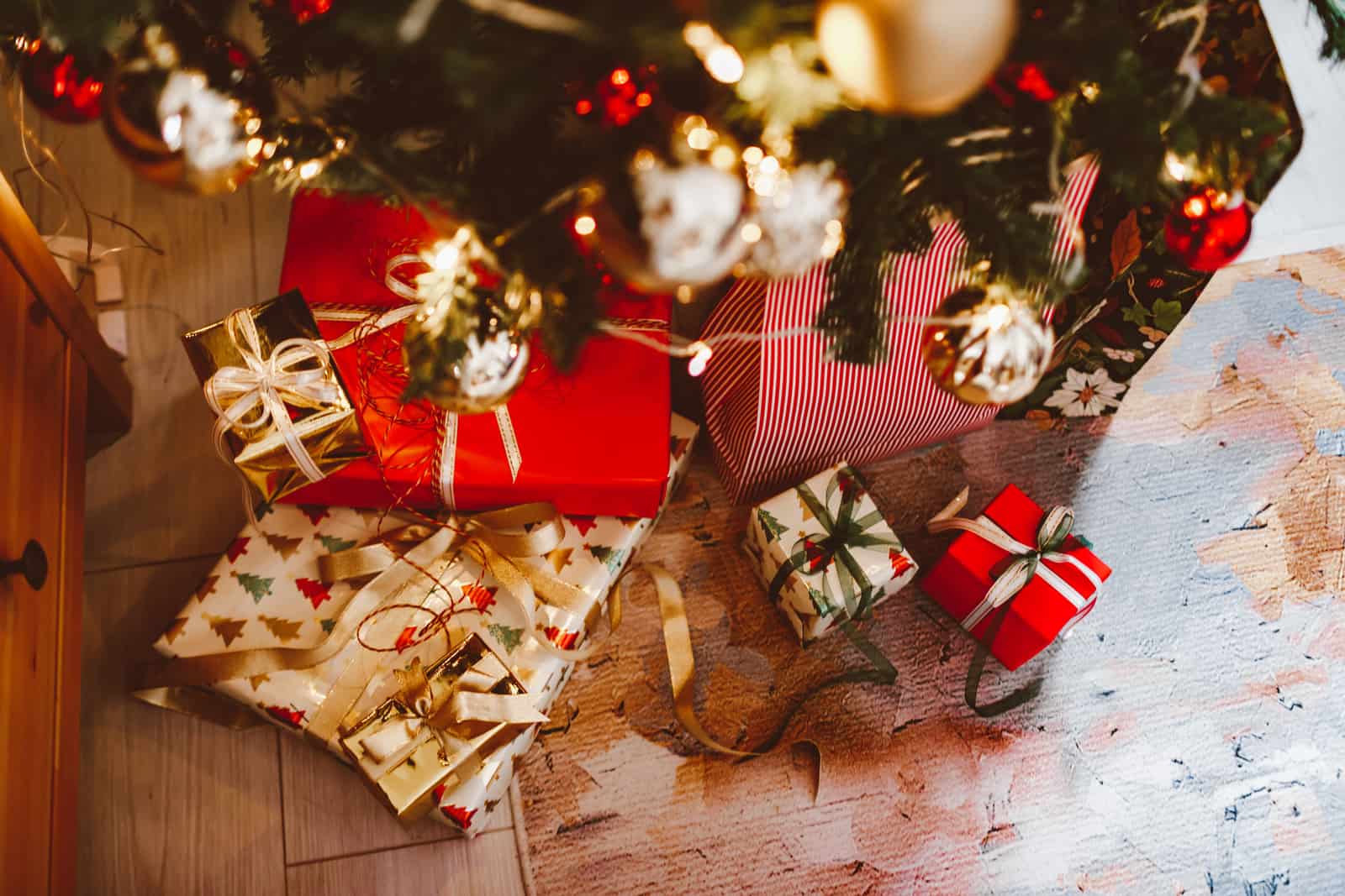 Wrapped gifts arranged under a tree in warm light